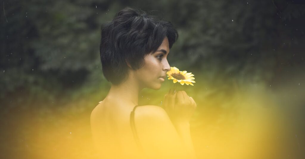 Portrait of a woman outdoors holding a sunflower, with a soft, dreamy mood.
