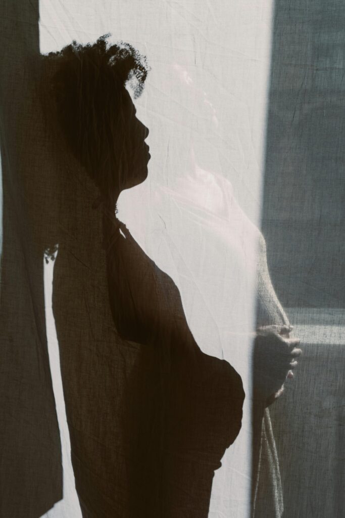 pexels photo 5854042 5854042 Artistic silhouette of a pregnant woman standing behind a curtain, highlighting her baby bump.